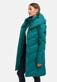 Teal puffer coat with a hood, featuring diamond quilted texture, snap closure, and subtle logo detail on the sleeve.