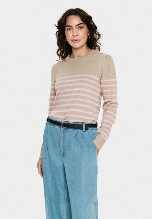 Beiger und rosa gestreifter Pullover aus weichem Strick, mit Rundhalsausschnitt und langen Ärmeln. Kombiniert mit hellblauen Hochbundhosen und schwarzem Gürtel.