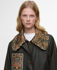 Dark green jacket with a large embroidered collar in orange and green floral patterns. Features a chest patch with brand name and floral design.