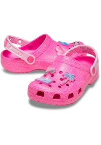 Ροζ πλαστικές σαμπό με υφασμάτινη υφή, πλαϊνό λουράκι, οπές αερισμού και διακοσμητικά charms με ένα φοινικόδεντρο και ένα παιχνιδάκι αυτοκινάκι.