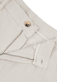 Pantaloni beige in cotone con zip e chiusura a bottone. Tessuto testurizzato con dettagli a righe diagonali.
