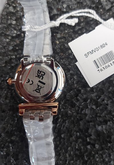 Armbandsur i rostfritt stål med silver- och roséguldfinish. Har ett vitt plastarmband, rund urtavla och synliga varumärkesmarkeringar på baksidan.