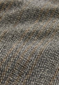 Textured woven fabric in gray tones with a herringbone pattern, featuring flecks of brown and a soft, wool-like finish.