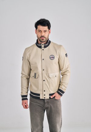 Beige leren jas met een geribbelde zwarte kraag, drukknoopsluiting aan de voorkant, twee borstzakken en contrasterende gestreepte manchetten. Subtiel logo detail.