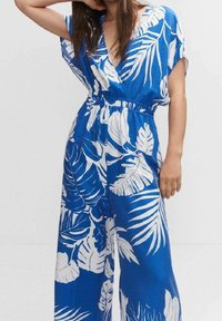 Modrý overal s bílými tropickými vzory listů, krátkými batwing rukávy, elastickým pasem a širokými nohavicemi. Lehká textilie.
