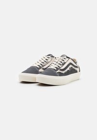 Sneakers with a navy canvas upper, white leather accents, and beige laces. Features a rubber sole and classic Vans design elements.