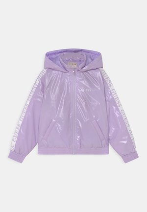 Giacca a vento lucida color lilla con cappuccio, zip frontale, tasche laterali e branding stampato in bianco sulle maniche. Polsini ed orlo elasticizzati.
