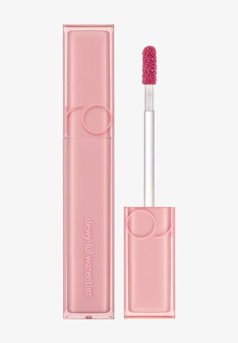 Tube rose de teinte hydratante avec une finition douce au toucher, accompagné d'un applicateur en pied de cerf avec une pointe texturée pour une application uniforme.