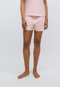 Φωτεινά ροζ βαμβακερά σορτς με ελαστική μέση, χαλαρή εφαρμογή και μικρό μήκος, σε συνδυασμό με ένα ταιριαστό ροζ τοπ.