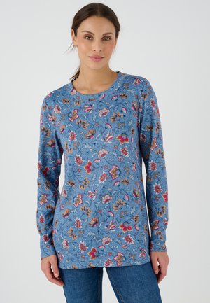 Blauwe blouse met lange mouwen en bloempatronen in rood, oranje en wit. Ronde halslijn en zachte textuur. Gecombineerd met denim jeans.