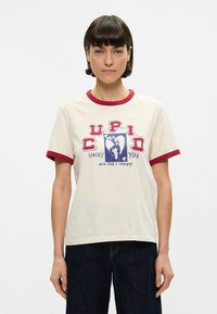 Βαμβακερό T-shirt σε κρέμ απόχρωση με κόκκινες λεπτομέρειες στον λαιμό και τα μανίκια. Διακοσμείται με εκτύπωση γραφικού σχέδιο ενός φιγούρας και κειμένου σε μπλε και κόκκινο. Άνετη εφαρμογή.