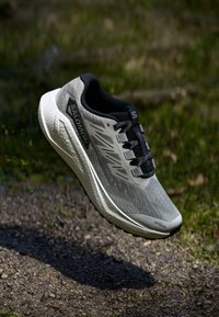 Chaussure de course légère en gris et noir, dotée d'une tige en mesh respirant, d'une surface texturée et de lacets contrastés avec une semelle rembourrée.