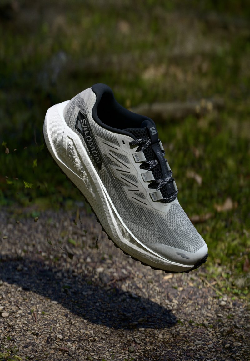 Scarpa da corsa leggera in grigio e nero, con tomaia in mesh traspirante, superficie testurizzata e lacci a contrasto, dotata di suola ammortizzata.