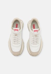 White and beige sneakers featuring a smooth textile upper, beige suede accents, round toe, lace-up design, and red "CAMPER" logo on the tongue.