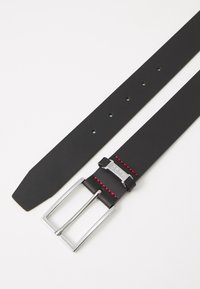 Zwarte leren riem met een zilveren rechthoekige gesp. Heeft rode stiksels en vijf gaatjes voor aanpassing langs de band.