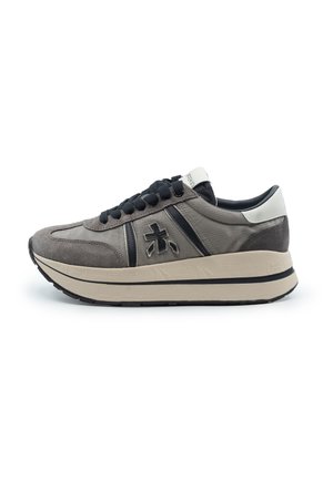 Grauer und schwarzer Sportschuh mit schwarzen Schnürsenkeln, beiger Sohle, weißem Fersendetail und schwarzem Kreuzlogo an der Seite.