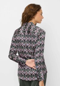 Langærmet bluse i et sort, grønt og pink slangeprint mønster. Blødt stof med en glat overflade, med en klassisk krave og knaplukning ved håndleddene.