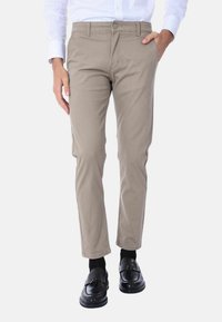 Chinos beige a vestibilità slim, realizzati in cotone, con tasche laterali, chiusura con bottone frontale, abbinati a mocassini neri.