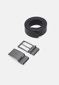Svart belte laget av glatt materiale med to metallspenner i matte mørkegrått, med merkevarenavnet preget på en av spenne.