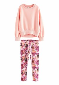 Felpa rosa con collo rotondo e polsini a coste, abbinata a leggings floreali con tonalità di rosa, viola e nero in un motivo ad acquerello.