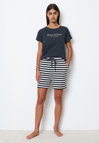 Mörkblå t-shirt med korta ärmar, med vit text. Svart och vit randiga shorts med elastisk midja och sidofickor.