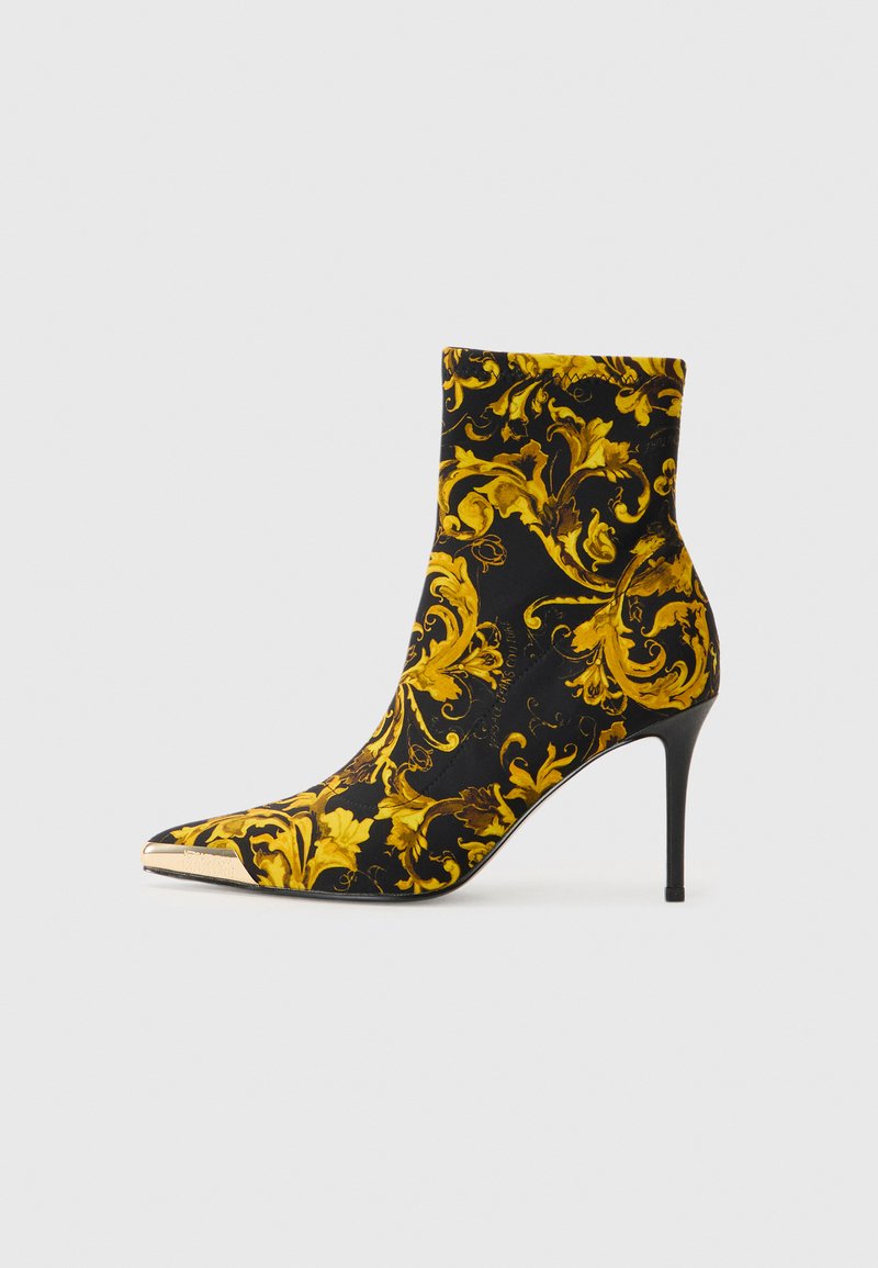 Zwarte enkellaars met een ornate goud- en gele bloemenpatroon, spitse neus en slanke stilettohak, met een metallic punt.