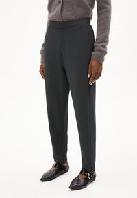 Grijze, op maat gemaakte broek gemaakt van een gladde, rekbare stof, met een hoge taille en zijzakken, gecombineerd met zwarte puntige flats en een enkelbandje.