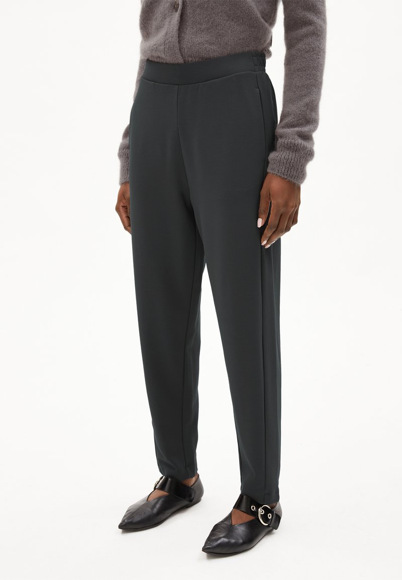 Grijze, op maat gemaakte broek gemaakt van een gladde, rekbare stof, met een hoge taille en zijzakken, gecombineerd met zwarte puntige flats en een enkelbandje.