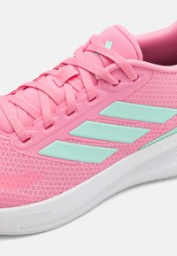 Rosa idrettssko med mesh-overdel, tre mintgrønne side-striper, flate lisser og hvit Cloudfoam såle. Glatt tekstur med pustende design.
