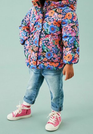 Floral puffer jacket featuring vibrant pink and blue flowers; paired with light-wash denim and pink sneakers with white soles and laces.