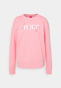 Sweat-shirt rose à manches longues avec col rond, poignets et ourlet côtelés, arborant un logo texte "HUGO" superposé en blanc et noir sur le devant.