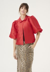Red satin cropped jacket with puff sleeves and a rounded collar, paired with a leopard print skirt, featuring a front slit and pockets.
