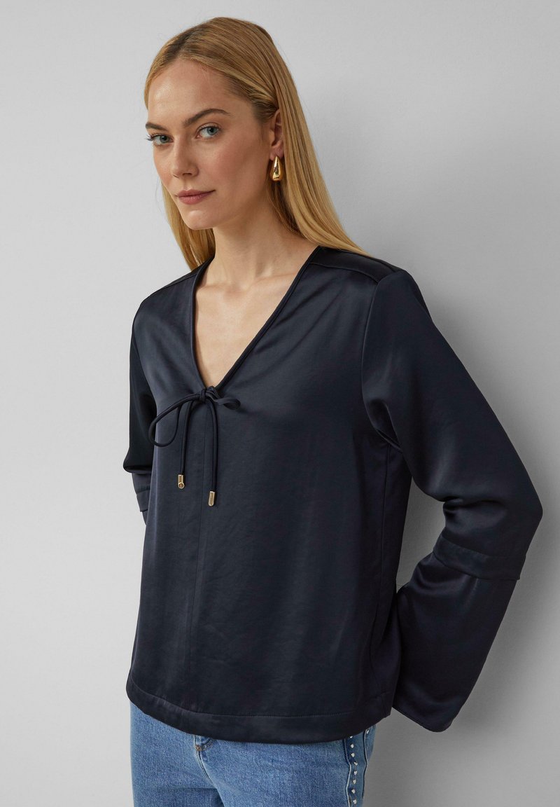 Marineblouse met een diepe V-hals, trekkoorddetail en lange mouwen. Glad satijnmateriaal met een ontspannen pasvorm en subtiele glans.