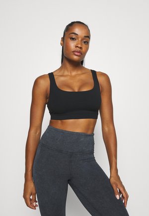Sutiã desportivo preto com decote quadrado e alças largas, combinado com leggings de cintura alta em cinza escuro com uma textura subtil.