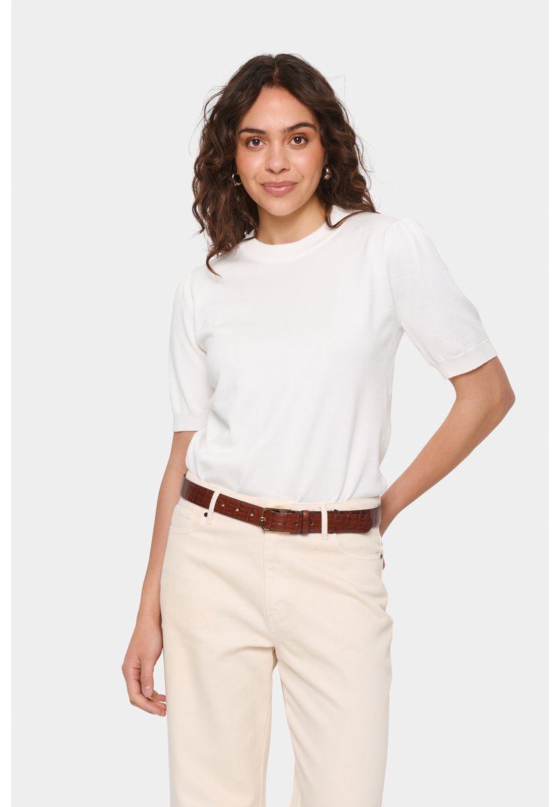 Top bianco a maniche corte con scollo tondo, abbinato a pantaloni beige e una cintura marrone testurizzata. Tessuto morbido con un leggero luccichio.