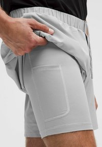 Pantalones cortos de malla gris claro con una cinturilla elástica y un bolsillo lateral visible. La tela tiene un patrón texturizado y un ajuste relajado.