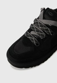 Sneaker nera con tomaia in camoscio, pannelli in rete e lacci a motivi a contrasto. Sole in gomma spesso e dettaglio del logo sulla linguetta.