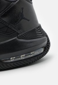 Musta lenkkari, jossa on teksturoitu nahkaosa, varustettuna kumipohjalla, jossa on kuvioitu pito, ja näkyvällä ilmapehmusteelle.