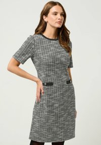 Vestito a maniche corte in un tessuto nero e bianco testurizzato, caratterizzato da due bottoni neri a contrasto in vita e scollatura rotonda classica.