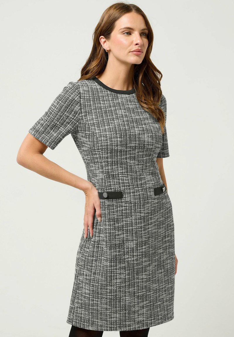 Vestito a maniche corte in un tessuto nero e bianco testurizzato, caratterizzato da due bottoni neri a contrasto in vita e scollatura rotonda classica.