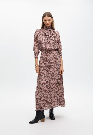 Maxi-jurk met luipaardprint in roze en zwart, met een hoge hals, strikdetail en lange mouwen, gecombineerd met zwarte enkellaarsjes.