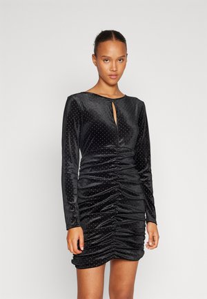 Black velvet dress with long sleeves, keyhole neckline, and gathered ruching detail. Adorned with silver stud embellishments throughout.