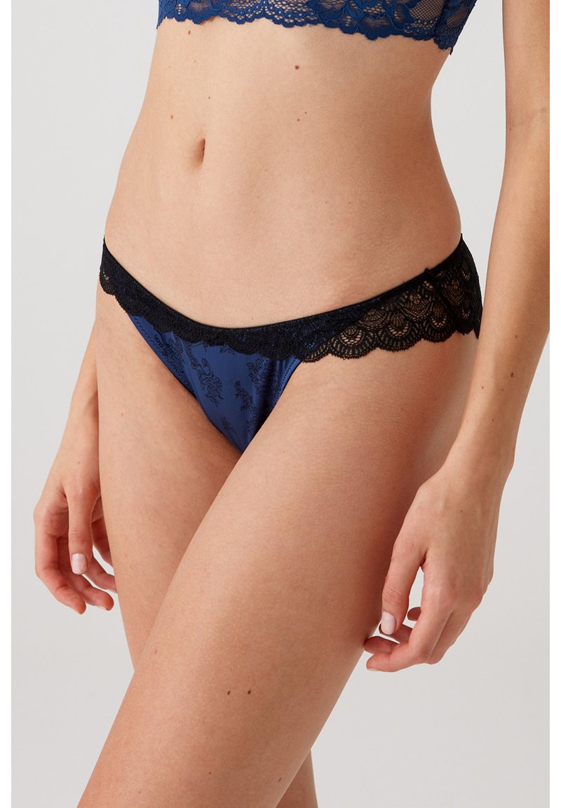 Blauwe thong met kant, gemaakt van satijnen stof, met een elastische tailleband en complexe bloemmotieven langs de randen.