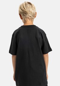 Mustalla lyhytnuusikäisellä t-paidalla, jossa on klassinen pääntie, valmistettu puuvillasta, sileäpintainen ja minimalistisella muotoilulla, näkyy takaa.