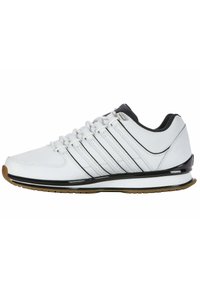 White athletic shoes with a smooth leather upper, black accents, six eyelets, and a gum rubber outsole. Features a cushioned sole and sleek design.