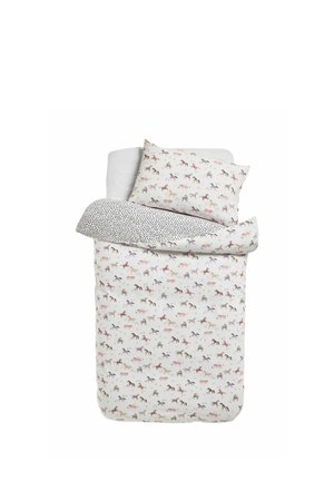 Einzelbett mit weißer Bettwäsche mit kleinen Pferdeprints und einem Kissen mit passendem Pferdemotiv, das die Rückseite mit schwarzen Flecken zeigt.