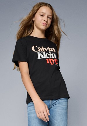 Juodas medvilninis marškinėlis su ryškiu daugiaspalviu logotipu: "Calvin Klein nyc" kreminės, raudonos ir juodos spalvų derinyje. Klasikinis kirpimas, trumpomis rankovėmis.