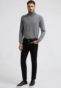 Hall hall turtleneck-kampsun pehmest kootud materjalist, kombineeritud kitsaste mustade teksade ja mustade tennistega. Vööl on silmapaistev hõbedase pandlaga vöö.