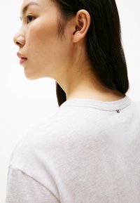 Grå bomuld t-shirt med afslappet pasform, rund halsudskæring og korte ærmer. Har en lille rød, hvid og blå detalje ved baghalsen.