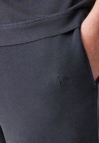 Temno modri jogging hlače iz bombažnega blaga z teksturirano površino. Imajo diskretno logo na strani in standardne stranske žepke.